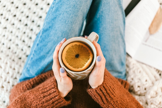 Femme buvant une tasse de tisane chaude à l'orange