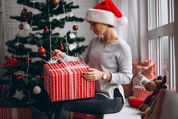 Femme avec des cadeaux de Noël par sapin de Noël