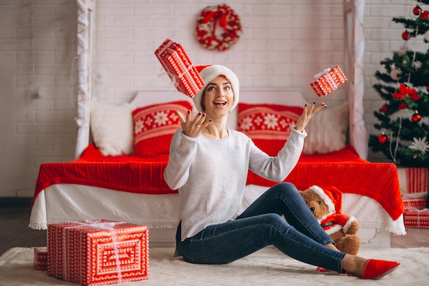 Femme avec des cadeaux de Noël par sapin de Noël