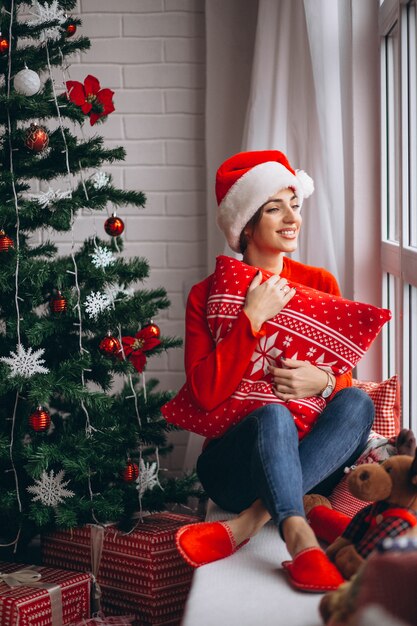 Femme avec des cadeaux de Noël par sapin de Noël