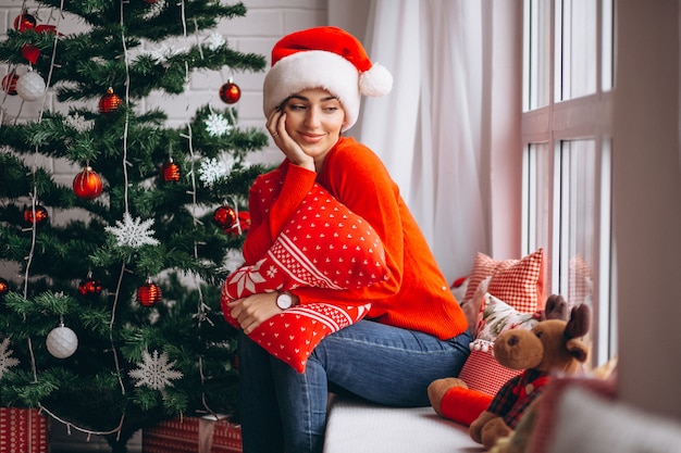 Femme avec des cadeaux de Noël par sapin de Noël