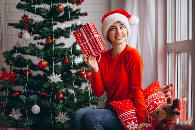 Femme avec des cadeaux de Noël par sapin de Noël