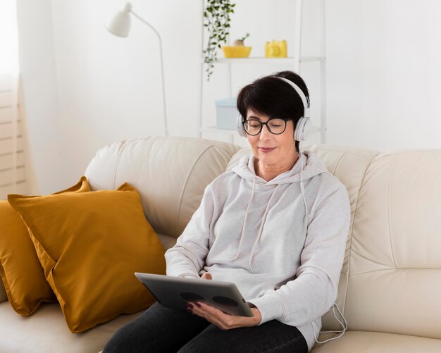 Femme sur canapé avec tablette et écouteurs
