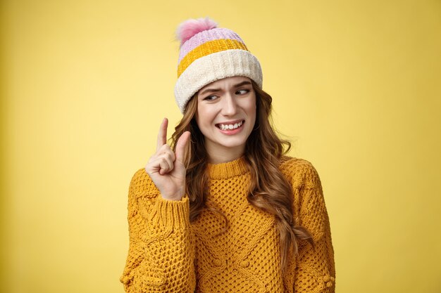 Une femme capricieuse et attrayante mécontente décrivant un petit objet montre une petite chose qui grince des dents n'aime pas la déception regarde des doigts contrariés, décrivant un petit salaire nouveau travail, debout fond jaune maladroit