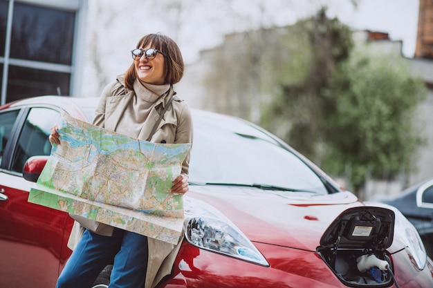 Femme avec carte de voyage voyageant en voiture electro