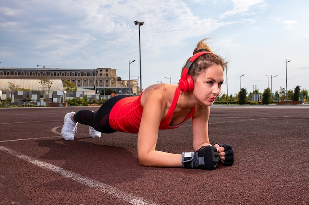 Femme avec un casque rouge et des tenues de sport faisant de la gymnastique.