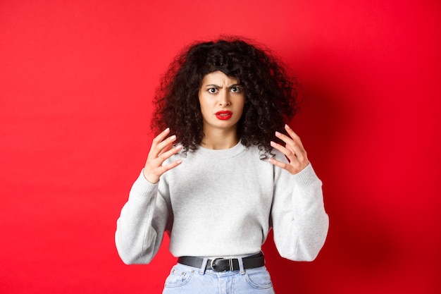 Femme caucasienne en colère fronçant les sourcils et levant les mains folles veut étrangler ou tuer quelqu'un d'ennuyeux stan ...