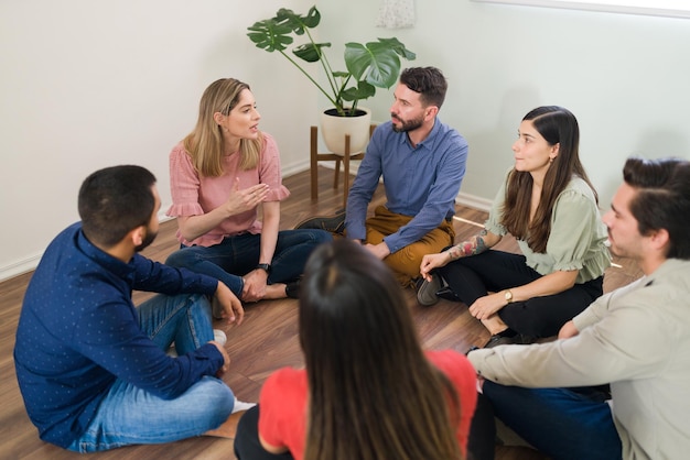 Femme caucasienne partageant son expérience de la toxicomanie avec son groupe de réadaptation. Jeune membre participant à une thérapie de groupe