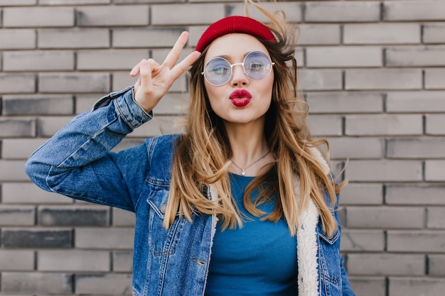 Femme caucasienne rêveuse dans des vêtements à la mode sur le mur de briques