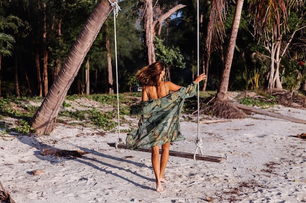 Femme caucasienne tatouée en short en jean et top court à la mode vert sur la plage