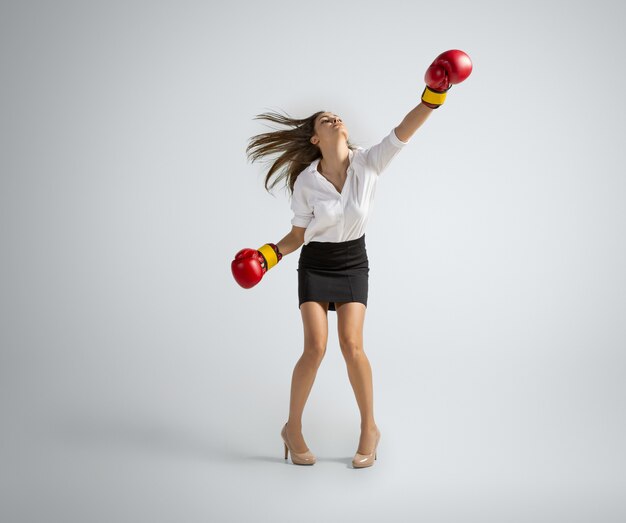 Femme caucasienne en vêtements de bureau boxe sur gris