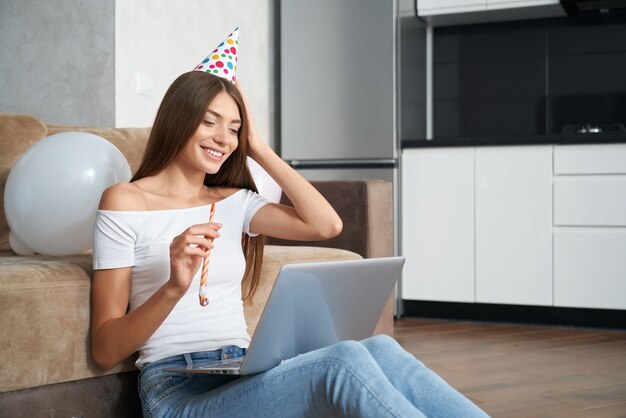 Femme célébrant son anniversaire seule à la maison par appel vidéo