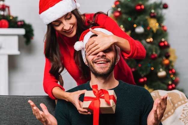 Femme en chapeau de fête fermant les yeux sur un homme surpris