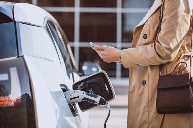 Femme chargant une voiture électrique à la station-service électrique