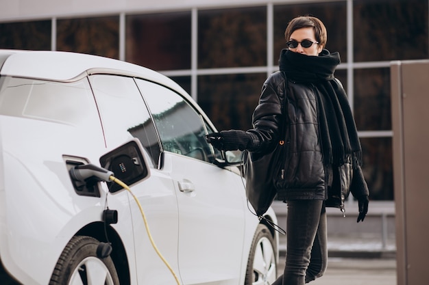 Femme chargeant une voiture électrique dans la rue