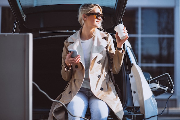 Femme chargeant une voiture électrique à la station d&#39;essence électrique