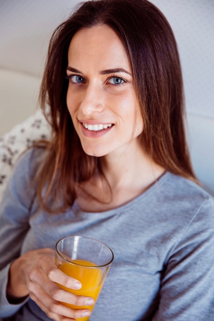 Femme charmante avec du jus au lit