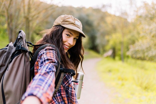 Femme charmante avec thermos offrant remorquage à pied avec elle