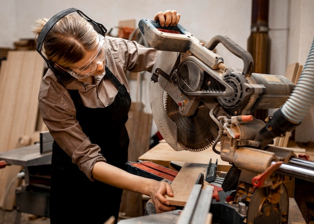 Femme charpentier dans le studio à l'aide d'une scie électrique