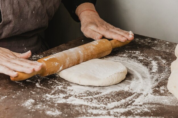 Femme chef à l'aide de rouleau à pâtisserie sur la pâte à pizza