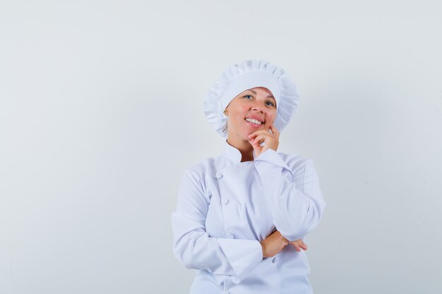 femme chef debout dans la pensée pose en uniforme blanc et à la joyeuse.