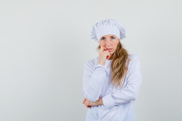 Femme chef debout dans la pensée pose en uniforme blanc et à la recherche d'impuissance.