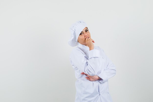 Femme chef debout dans la pensée pose en uniforme blanc et à la recherche raisonnable.