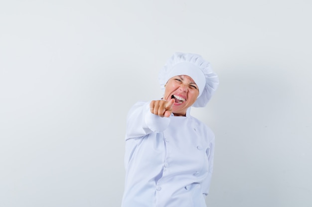 femme chef pointant vers l'avant en uniforme blanc et à la recherche de plaisir.