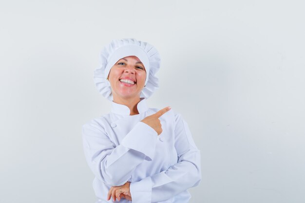 femme chef pointant vers le côté droit en uniforme blanc et à la recherche de plaisir.