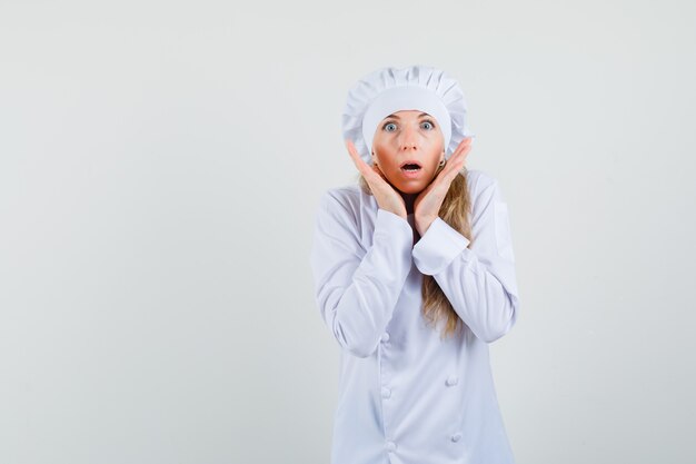 Femme chef tenant la main près du visage en uniforme blanc et à la peur