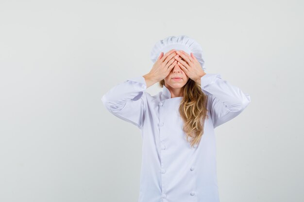 Femme chef en uniforme blanc cachant les yeux derrière les mains et à la peur