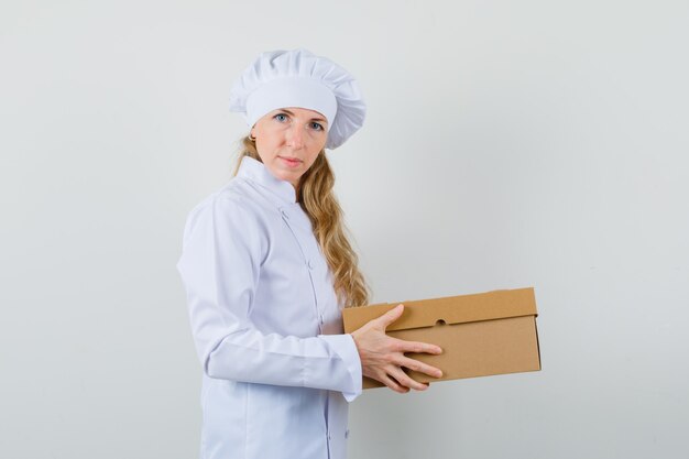 Femme chef en uniforme blanc tenant une boîte en carton