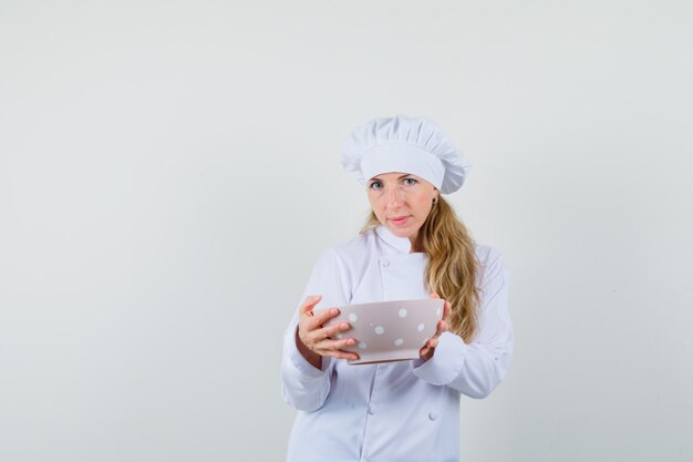 Femme chef en uniforme blanc tenant un bol