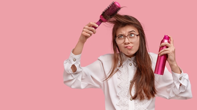 Femme en chemise blanche coiffant ses cheveux