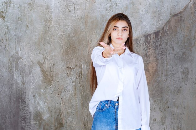 femme en chemise blanche debout sur un mur de béton et remarquant la personne autour.