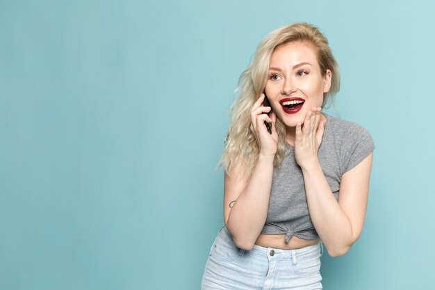 Femme en chemise grise et jeans bleu vif, parler au téléphone