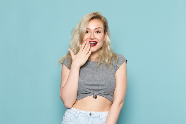 Femme en chemise grise et jeans bleu vif posign avec sourire