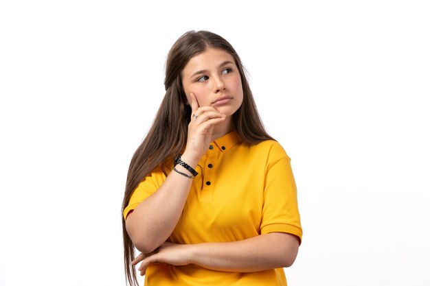 Femme en chemise jaune et jean bleu posant avec une expression de pensée sur les vêtements de modèle femme fond blanc