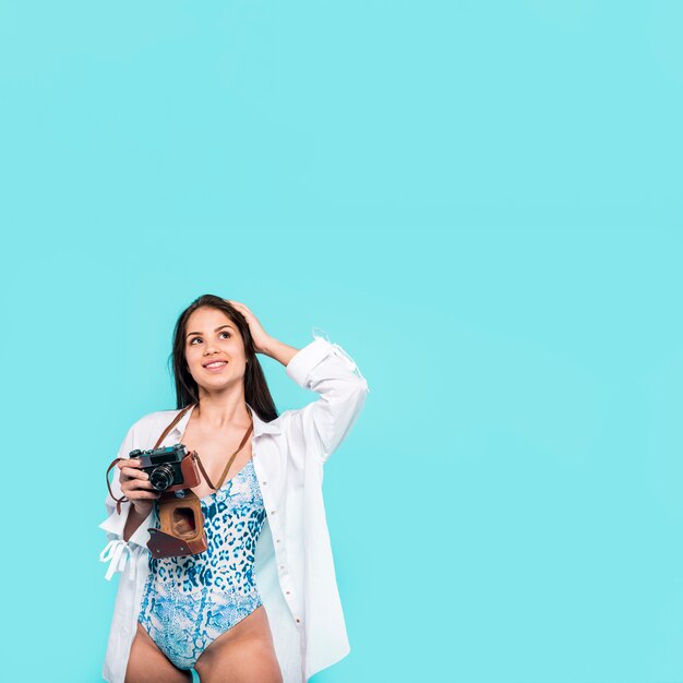 Femme en chemise et maillot de bain debout et tenant la caméra à la main