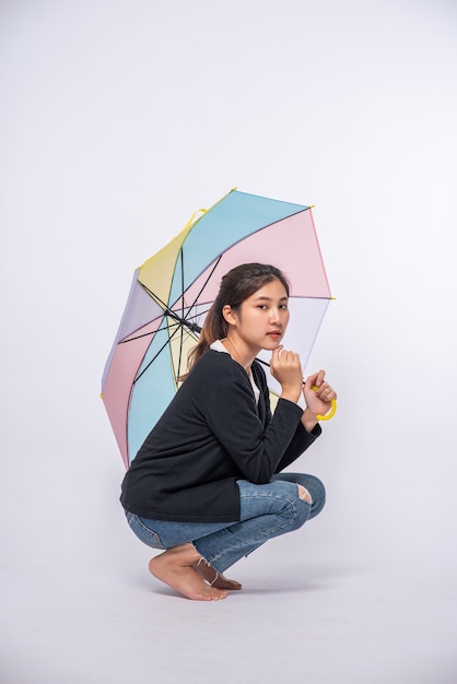 Femme en chemise noire assise et étalant un parapluie