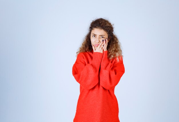 une femme en chemise rouge a l'air pessimiste ou triste.