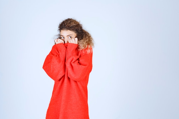 une femme en chemise rouge a l'air terrifiée et effrayée.