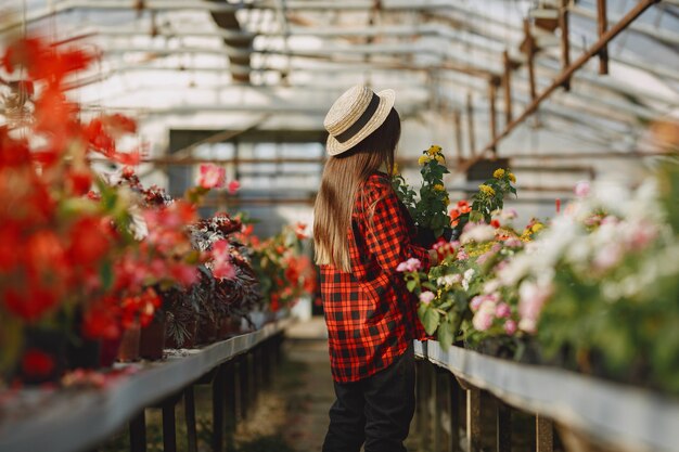 Femme en chemise rouge. Travailleur avec des pots de fleurs. Fille avec des plantes