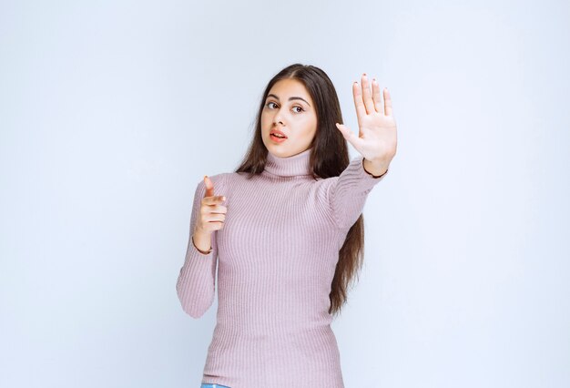 femme en chemise violette arrêter quelque chose avec les mains.