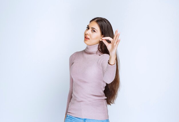 femme en chemise violette montrant le signe de la main de plaisir.