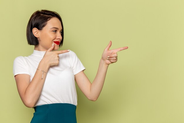 femme en chemisier blanc et jupe verte posant avec sourire