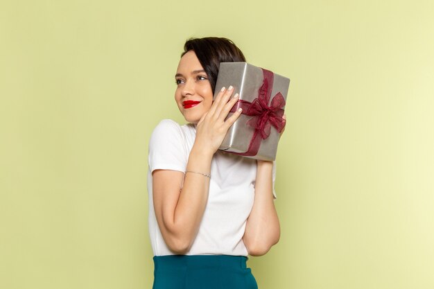 Femme en chemisier blanc et jupe verte tenant une boîte cadeau shopping