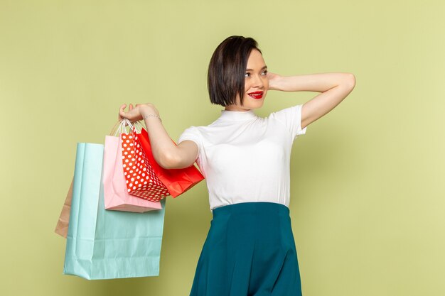 femme en chemisier blanc et jupe verte tenant des paquets shopping