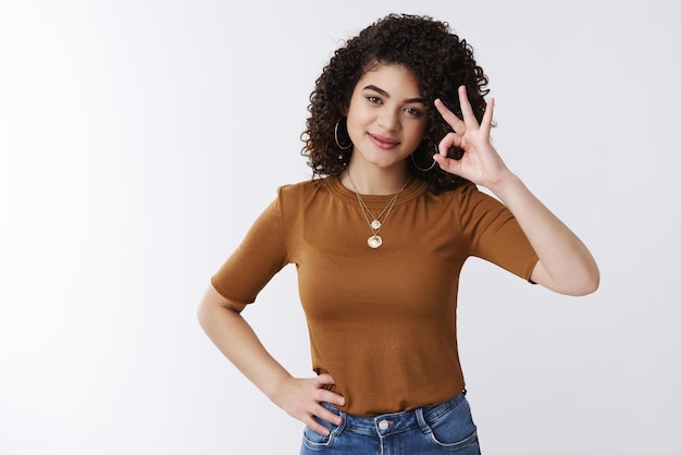 femme cheveux bouclés foncés montre bien le geste de confirmation assure que tout va bien, recommande une solution parfaite