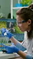 Photo gratuite femme chimiste prenant de l'adn liquide dans un tube à essai avec une micropipette mise dans une boîte de pétri analysant la mutation génétique